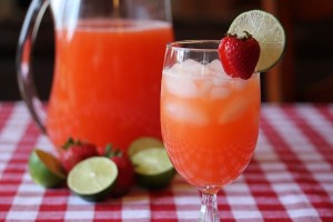 glass of strawberry limeade in front of a pitcher of limeade