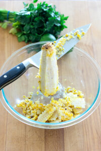 Demonstrating how to easily slice the corn off the cob for pan seared tilapia with spicy corn salsa recipe