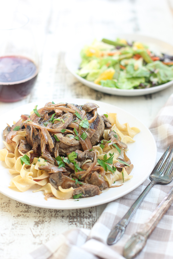 Filet mignon with stroganoff sauce plated and served with wine and salad