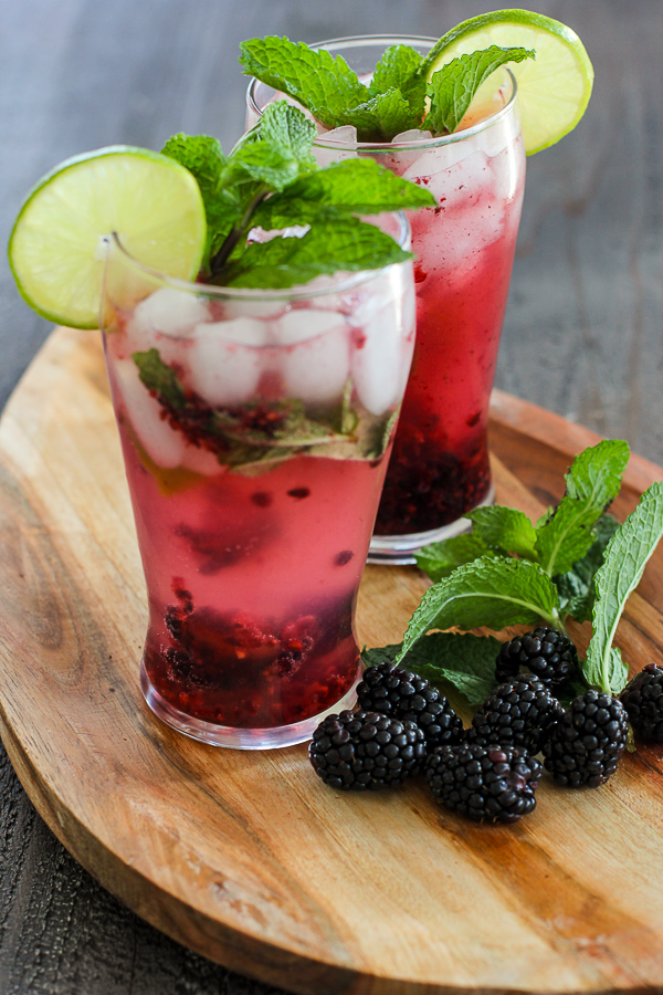 Two Blackberry Mint Spritzer Cocktail served in tall glasses and garnished with fresh lime and mint