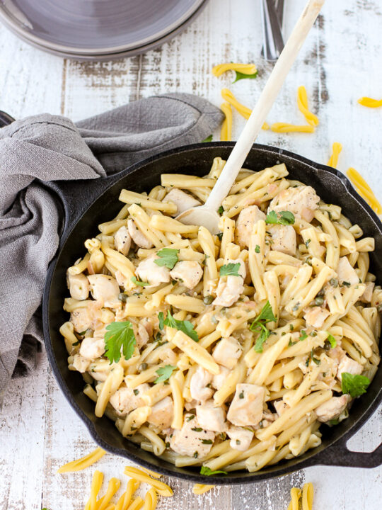 Finished chicken piccata pasta toss in a cast iron skillet ready to be served