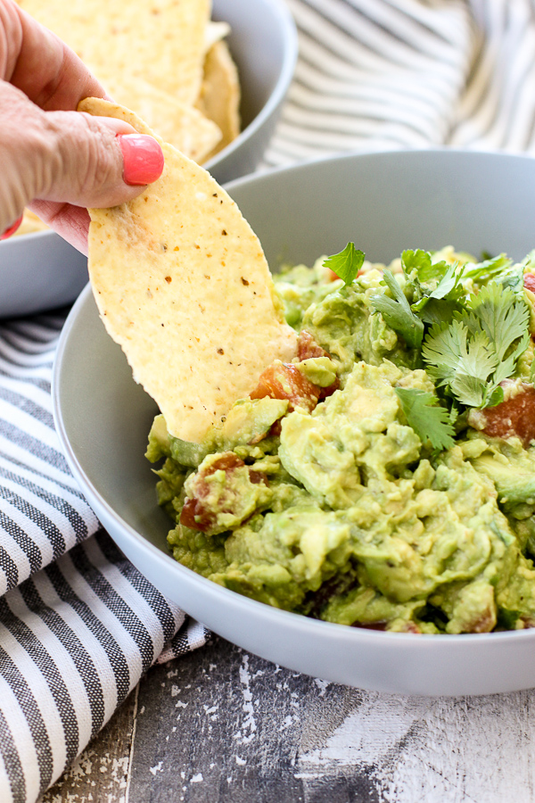 Dipping a tortilla chip into the finished guacamole