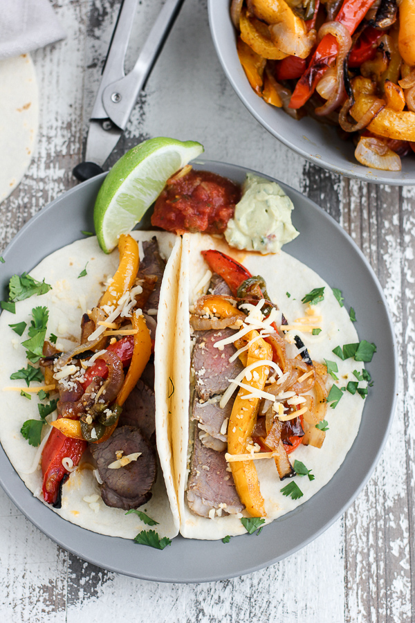 Overhead photo of fajitas serve on soft tortillas and topped with cheesed cilantro.