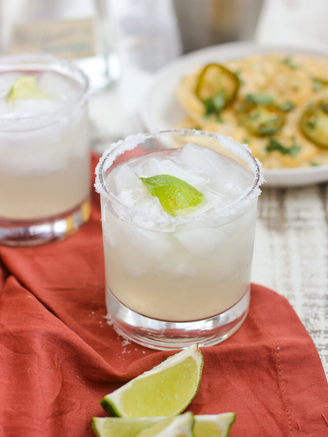 Close up of two glasses of the perfect skinny margarita with cheese dip in background